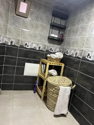 a bathroom with a black tiled wall with a shelf and baskets at Blue Palm apartment in Ouarzazate