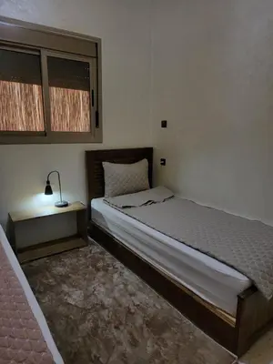 a bedroom with a bed and a lamp on a table at Blue Palm apartment in Ouarzazate