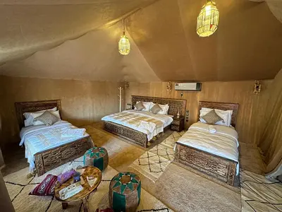 a room with two beds and a table and lights at Sahara Experience Luxury Camp in Merzouga
