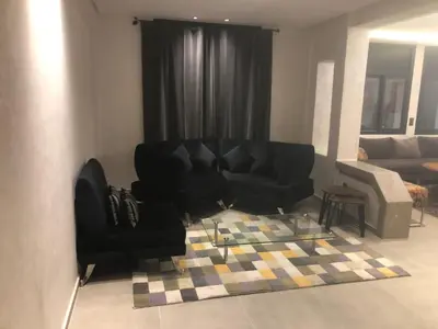 a living room with a black couch and a rug at Apartement in saada fez in Fès
