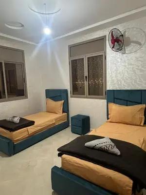 a bedroom with two beds and a clock on the wall at Sahara Luxury Apartments in Hassilabied