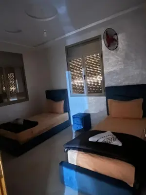 a bedroom with two beds and a clock on the wall at Sahara Luxury Apartments in Hassilabied