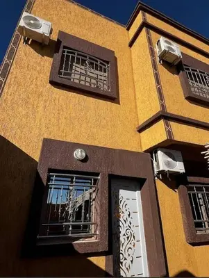 a yellow building with two windows and a door at Sahara Luxury Apartments in Hassilabied