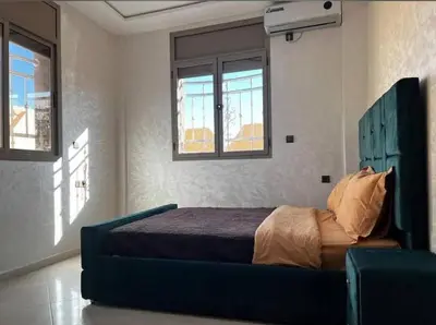 a bedroom with a bed in a room with windows at Sahara Luxury Apartments in Hassilabied