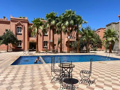 a patio with a table and chairs next to a pool at COMPLEXE TOURISTIQUE ARTIZANAL bab sahara in Oulad Akkou