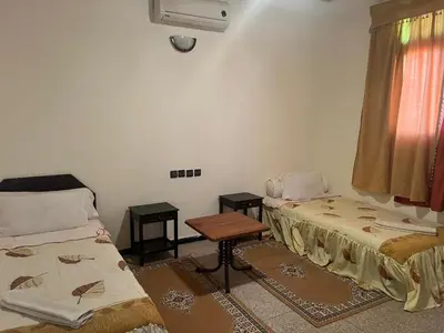 a room with two beds and a table and a window at COMPLEXE TOURISTIQUE ARTIZANAL bab sahara in Oulad Akkou