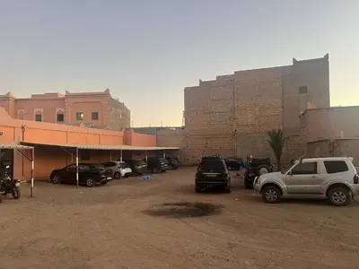 a parking lot with cars parked in front of buildings at COMPLEXE TOURISTIQUE ARTIZANAL bab sahara in Oulad Akkou