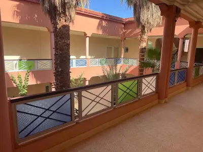 a balcony of a house with a fence and palm trees at COMPLEXE TOURISTIQUE ARTIZANAL bab sahara in Oulad Akkou