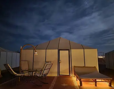 a tent with chairs and a table in front of it at irrigation desert camp in Merzouga