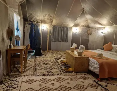 a room with a tent with a bed and a table at irrigation desert camp in Merzouga