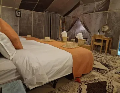 a bedroom with two beds in a tent at irrigation desert camp in Merzouga