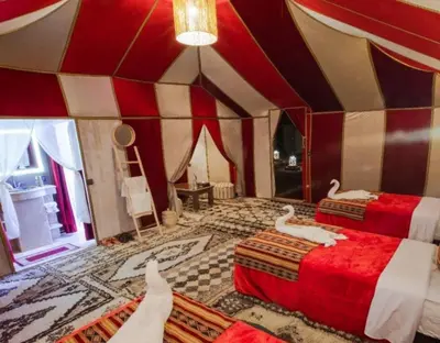 two beds in a room with red and white walls at Slik Sand Oasis Camp in Merzouga