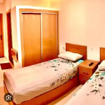 a small bedroom with two beds and a cabinet at Restinga in Oulad Akkou