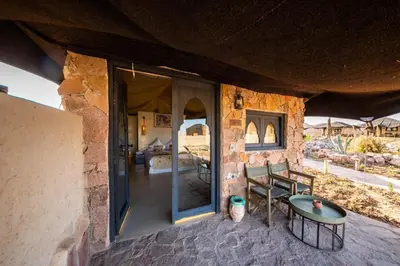 a stone house with a table and a bedroom at Les Bedouins Agafay in Oulad Akkou