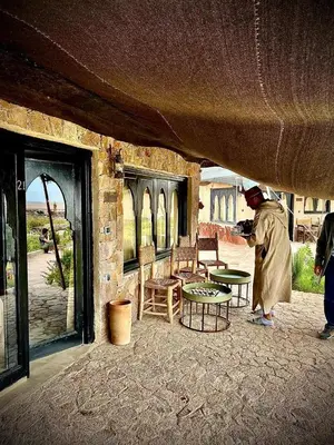 a person standing outside of a building with a table at Les Bedouins Agafay in Oulad Akkou