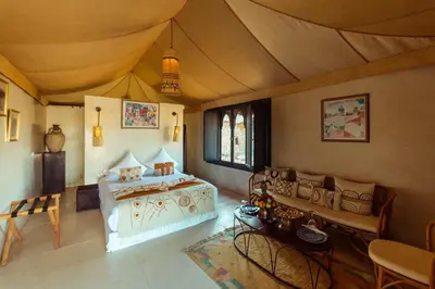 a room with a bed and a table and chairs at Les Bedouins Agafay in Oulad Akkou