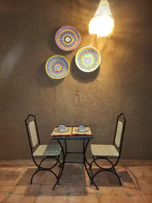 a table and two chairs with umbrellas on a wall at Dar Dallali in Mhamid