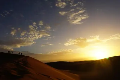 a group of people standing on top of a sand dune at Dar Dallali in Mhamid
