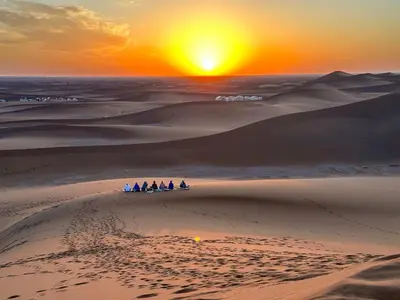 a group of people in the desert at sunset at Dar Dallali in Mhamid