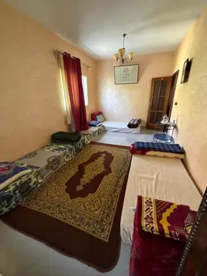 a room with two beds and a rug on the floor at Maison Merzouka - Rustic Stay in the Taza Countryside