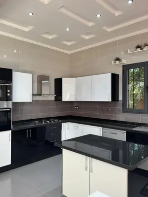 a large kitchen with white cabinets and black counter tops at Dar Jabal in Aït Zat