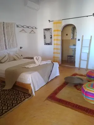 a bedroom with two beds and a table in it at L'oasis Du Bonheur in Aït Ben Haddou