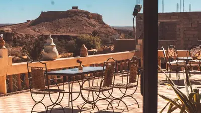 a table and chairs on a patio with a view at L'oasis Du Bonheur in Aït Ben Haddou