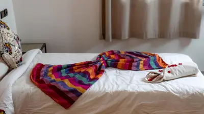 a blanket laying on top of a bed at L'oasis Du Bonheur in Aït Ben Haddou