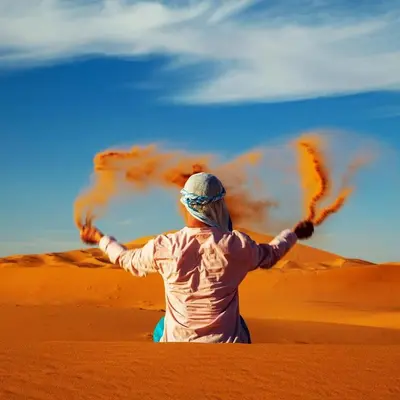 a woman in the desert with her arms outstretched at Under 1000 Stars Camp in Merzouga