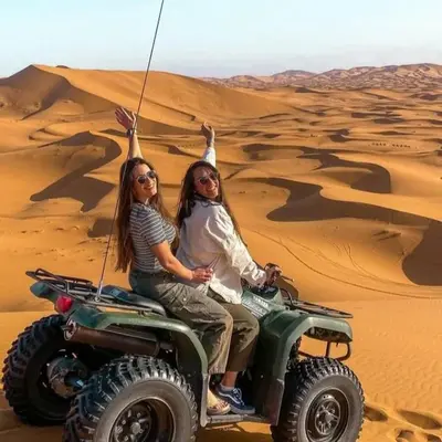 two women riding on a wheeler in the desert at Under 1000 Stars Camp in Merzouga