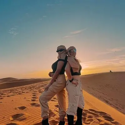 two women standing in the desert at sunset at Under 1000 Stars Camp in Merzouga