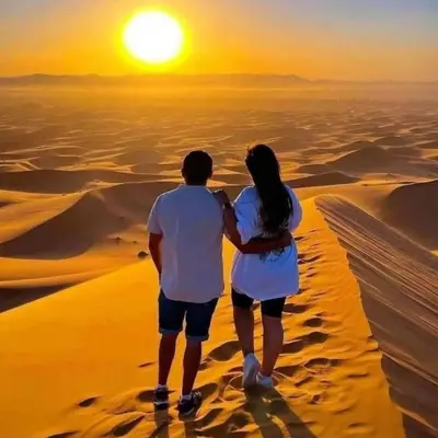 a couple standing in the desert watching the sunset at Under 1000 Stars Camp in Merzouga