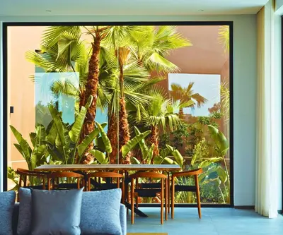 a dining room with a table and palm trees at Villa Timenkar - Moroccan spa and mountain panorama in Aghmat