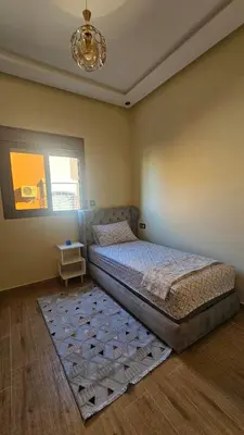 a bedroom with a bed with a rug and a chandelier at 2 bedroom apartment, low price & comfort in Oulad Akkou