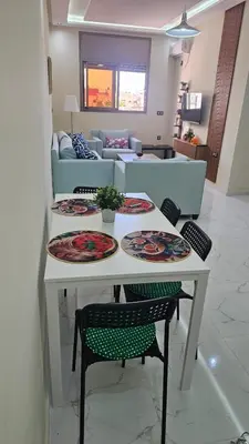 a table with plates on it in a living room at 2 bedroom apartment, low price & comfort in Oulad Akkou