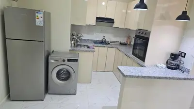a kitchen with a refrigerator and a washing machine at 2 bedroom apartment, low price & comfort in Oulad Akkou