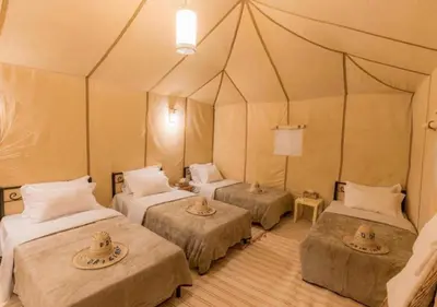 a room with three beds in a tent at Sahara Whisper Luxury Camp in Merzouga