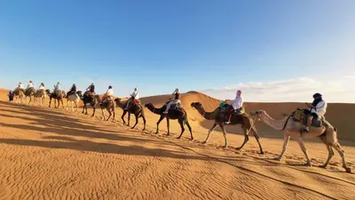 a group of people riding on camels in the desert at Sahara Whisper Luxury Camp in Merzouga