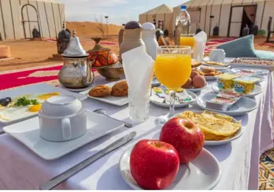 a table with food and drinks and apples on it at Sahara Whisper Luxury Camp in Merzouga
