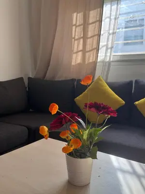 a vase with flowers on a table in front of a couch at Fleury in Fès