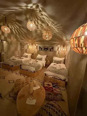 a room with two beds and a table and lights at Peaceful Luxury Camp in Merzouga
