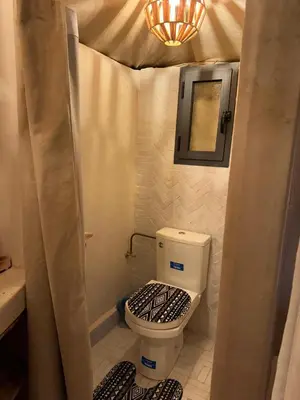 a small bathroom with a toilet and a mirror at Peaceful Luxury Camp in Merzouga