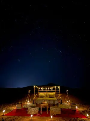 a bed in the middle of the desert at night at Peaceful Luxury Camp in Merzouga