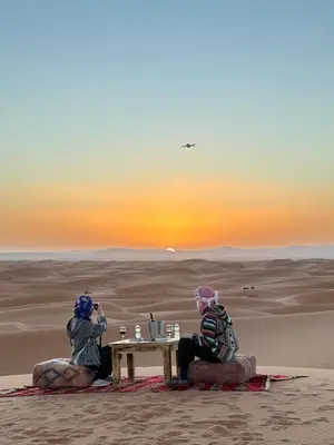 two people sitting at a table in the desert at Peaceful Luxury Camp in Merzouga