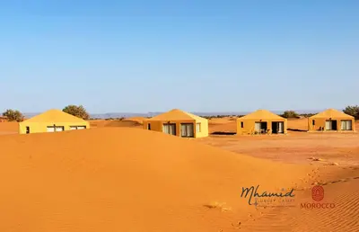 a group of houses on top of a sand mound at mhamid luxury camps in Mhamid El Ghizlane
