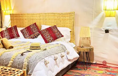 a bedroom with a bed with red and white pillows at mhamid luxury camps in Mhamid El Ghizlane