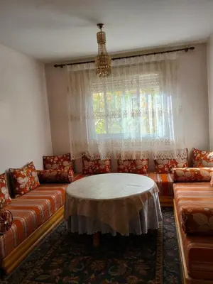 a living room with a couch and a table at Ravissante appartement dans les jardins in Oulad Akkou