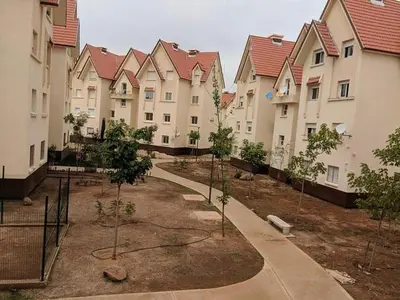 a row of apartment buildings with trees in the courtyard at Ravissante appartement dans les jardins in Oulad Akkou