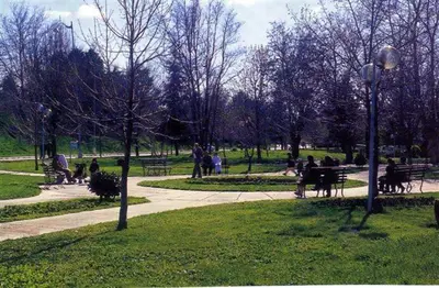 a park with people sitting on benches in the grass at Ravissante appartement dans les jardins in Oulad Akkou