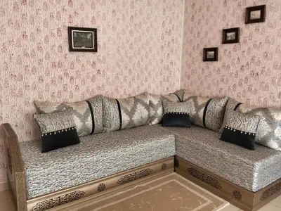 a couch in a room with pink wallpaper at Ravissante appartement dans les jardins in Oulad Akkou